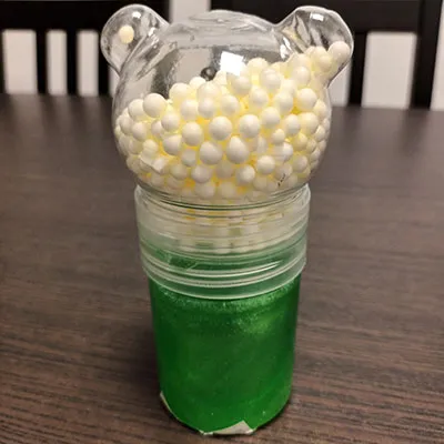 Mâzgă de jucărie verde. Vine împreună cu bile mici colorate, într-un compartiment separat.