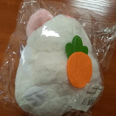 Jucărie albă, de pluș, în formă de iepure, cu morcov, urechi roz, ochi negri, un inel de coardă auto-retractabil și un atașament pentru coadă din plastic dur. Când inelul de coardă auto-retractabil este tras, iepurele dă din coadă.