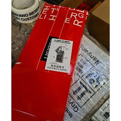 Brichetă metalică cu ceas încorporat. Pe partea de sus a brichetei este atașat un pistol mic.