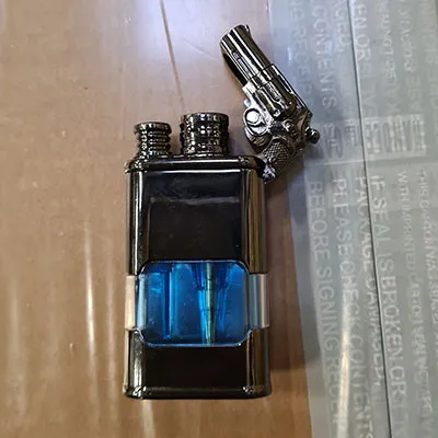 Brichetă metalică cu ceas încorporat. Pe partea de sus a brichetei este atașat un pistol mic.