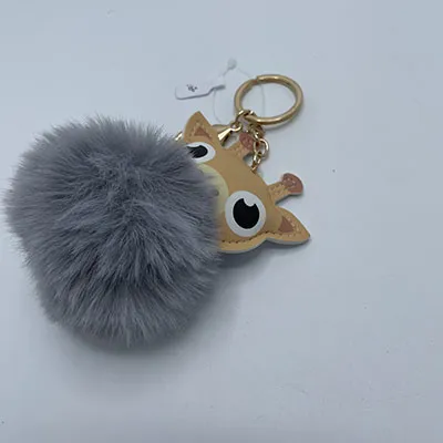 Jucărie de pluș, în formă de cap de girafă și pom pom gri, cu breloc.