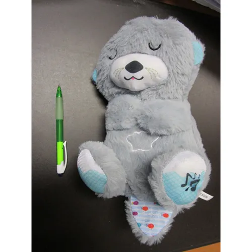 Jucărie gri umplută sub formă de vidră care simulează respirația cu efecte sonore, muzică și lumină, 30 cm, cu cutie de control acționată de baterie. Produs vândut online, în special prin intermediul grande-Peluche.com.