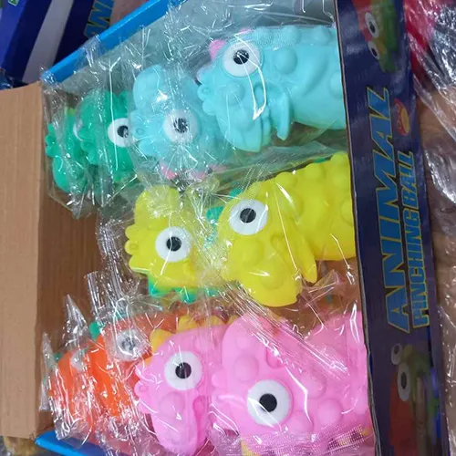 Jucărie din plastic de culoare roșie moale, care conține un LED, cu o creastă purpurie și ochi alb-negru care ies din cap atunci când jucăria este stoarsă.