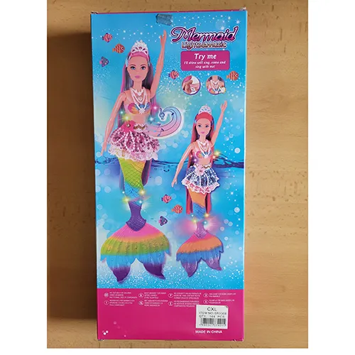 Păpușă cu păr lung și colorat, fustă din dantelă cu mărgele din plastic, corset din plastic colorat, perle din plastic pe gât și aripioare de pește. Produsul include, de asemenea, un delfin din plastic în roz sau albastru, o perie de păr, cochilii, scoici și o stea de mare. Dimensiune: 39 cm.