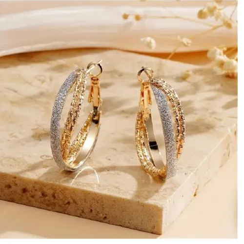 Pereche de cercei încrucișați din metal auriu, cu o bandă nemetalică de sclipici lipită de un inel. Sunt vizate toate loturile. Produs vândut online, în special prin intermediul TEMU (identificator unic de produs: 601099582004796).