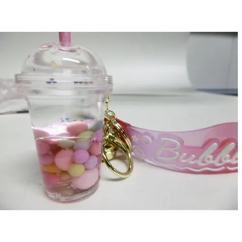 Trei brelocuri cu o figură de ceașcă de ceai cu bule. Figura din plastic conține două lichide neamestecabile (roz și limpede) în recipiente sigilate cu un dop din plastic de cauciuc. Produs vândut online, în special prin intermediul Shein (identificator de produs, SKU: sc2407277808880181).