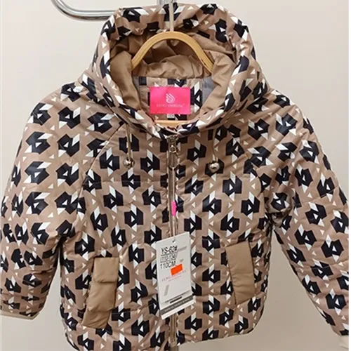 Jachetă destinată copiilor de vârstă mică, cu un top din material textil de culoare crem matlasat cu dungi orizontale, imprimat cu figuri obișnuite alb-negru. Hota utilizează un șnur elastic funcțional sub forma unei bucle, capetele buclelor ies liber cu aproximativ 7 cm.