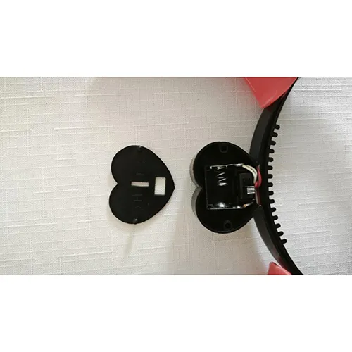 Bandă strălucitoare din plastic de jucărie în formă de coarne diavolești, acționată de baterie. În mijlocul benzii de susținere există un capac în formă de inimă pentru două baterii AG13.