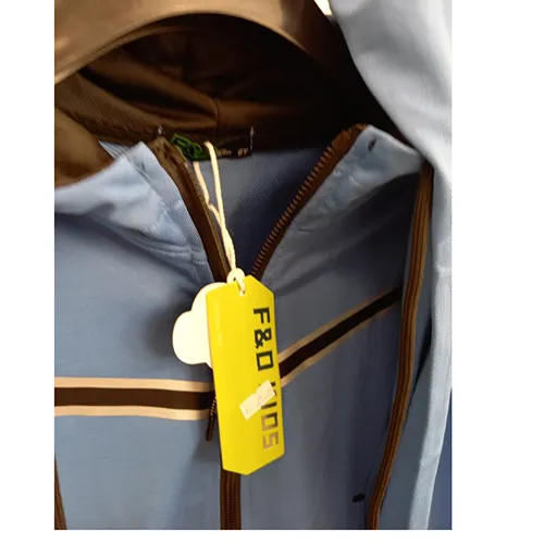 Set de îmbrăcăminte pentru copii destinat copiilor de vârstă mică, confecționat din material tricotat textil albastru deschis. Este compus dintr-un jumper cu glugă, fermoar și buzunare inserate. Capota are un cordon textil funcțional cu șnur, cu capete libere de aproximativ 24 cm lungime. Include, de asemenea, o pereche de pantaloni din material tricotat textil albastru deschis și cu buzunare inserate.