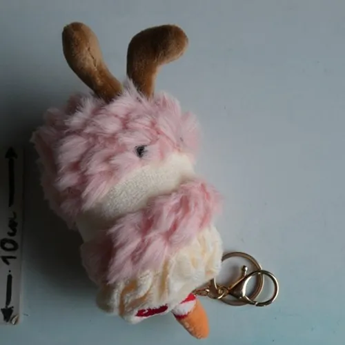 Breloc cu o jucărie moale în formă de tort de ziua de naștere cu ochi de plastic și o încuietoare metalică aurie. Produs vândut online, în special prin intermediul TikTok.