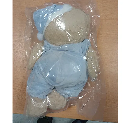 Jucărie moale în formă de urs cu ochi negri din plastic, îmbrăcată în pijama albastră și o pălărie de noapte potrivită. Produs vândut online, în special prin intermediul TikTok.