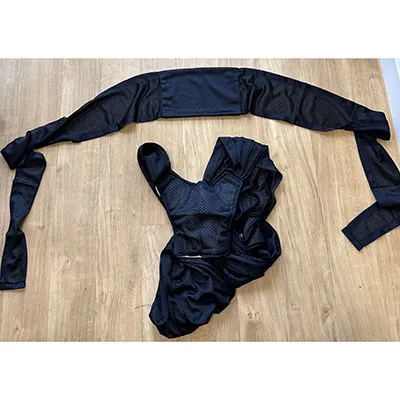 Sling pentru copii din două părți, fără deschideri integrate ale picioarelor, negru la exterior, cu o țesătură de plasă asemănătoare cu o cârpă și inserții albe căptușite în unele părți. Produs vândut online, în special prin intermediul AliExpress (Identificatori unici: 005007565256736-12000041320277361).