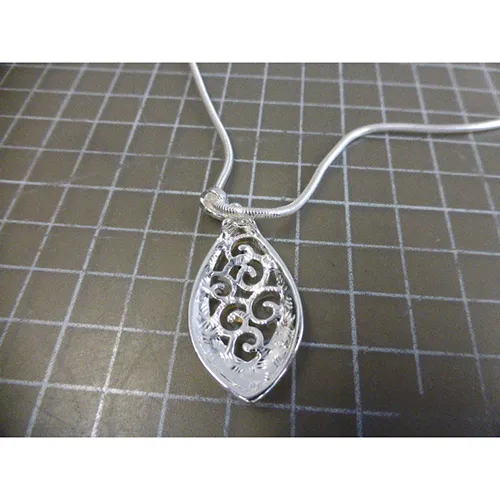 Colier metalic argintiu cu pandantive metalice argintii, negre și aurii, închidere și prelungitor de lanț.