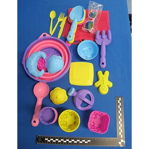 Set de jucării din plastic destinat plajei, format din 31 de părți, inclusiv o găleată pliabilă, un set de tacâmuri (cuțite, furculițe și linguri), o plasă, ochelari de soare, o cutie de udare, cinci unelte, două plăci și 17 forme. Produs vândut online, în special prin intermediul Amazon (ASIN B0DSVW25YQ).