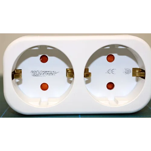 Adaptor cu soclu dublu. Dimensiuni: înălțime x lățime x adâncime = aproximativ 100 mm x 45 mm x 40 mm + bază.