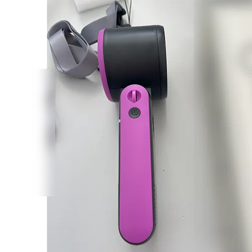 Ventilator pliabil portabil reîncărcabil, cu o carcasă din plastic în negru și roz, vândut cu un cablu de încărcare USB și o curea de încheietură.