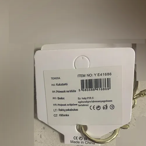 Ursulet moale de culoare maro deschis, cu ochi și nas din plastic negru, un colier de margele mici pe gât, cu un pandantiv metalic în formă de inimă atașat la acesta. Un inel metalic și un carabinier pentru agățat sunt atașate la produs.