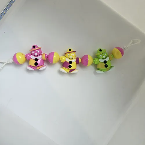 Zornăitoare de jucărie destinată copiilor care pot fi spânzurați. Se compune din trei figuri de bărbați de culori diferite, înșirate pe o frânghie, cu bile de plastic colorate între ele.