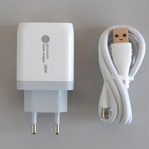 Încărcător USB alb cu un port USB-A și un port USB-C, furnizat cu un cablu de conectare USB separat. Intrări: 100-240V, 50-60Hz, 0,35A. Realizare: 5V/3A, 9V/2A, 12V/1.5A.