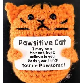 Jucărie croșetată moale în formă de siluetă de pisică cu ochi de plastic, ținând un card de plastic. Pe card scrie „Pawsitive Cat - Poate că sunt o pisică mică, dar cred în tine. Du-te și fă-ți treaba! Ești Pawsome!”.