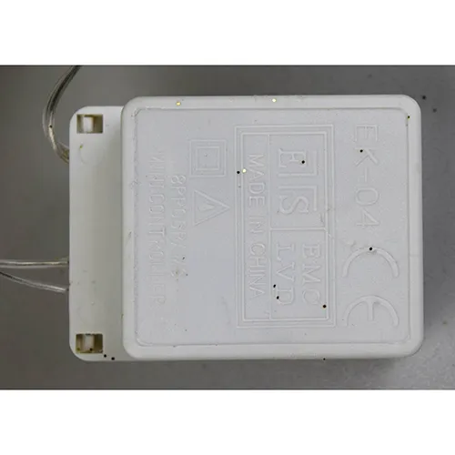 Corp de iluminat decorativ în formă de ren cu lumini LED galbene, corp cu sclipici auriu, fire transparente izolate și o cutie electronică albă de control marcată EK-04. Produsul este livrat cu un set de extensie a cablului.