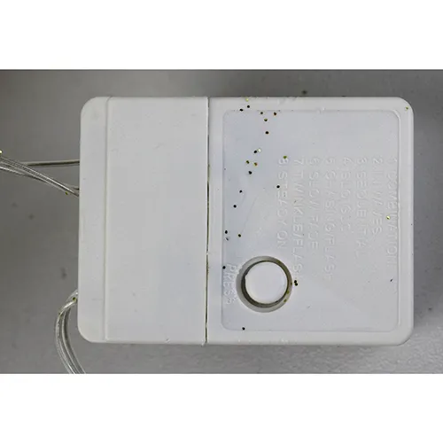Corp de iluminat decorativ în formă de ren cu lumini LED galbene, corp cu sclipici auriu, fire transparente izolate și o cutie electronică albă de control marcată EK-04. Produsul este livrat cu un set de extensie a cablului.