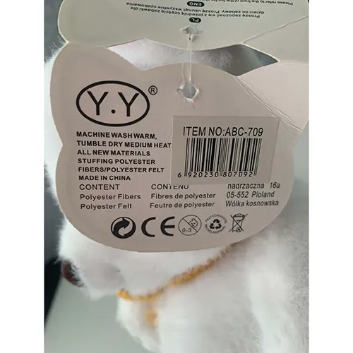 Ursuleț de pluș alb moale din material textil și umplut cu umplutură moale. Are un nas maro, marcaje decorative ale labei și o eșarfă tricotată galbenă legată în jurul gâtului.